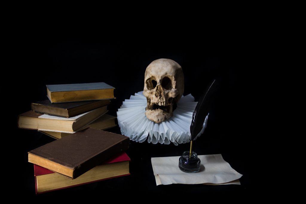 Books with a quill, inkwell, skull and gola, representing Miguel de Cervantes, writer of Don Quixote